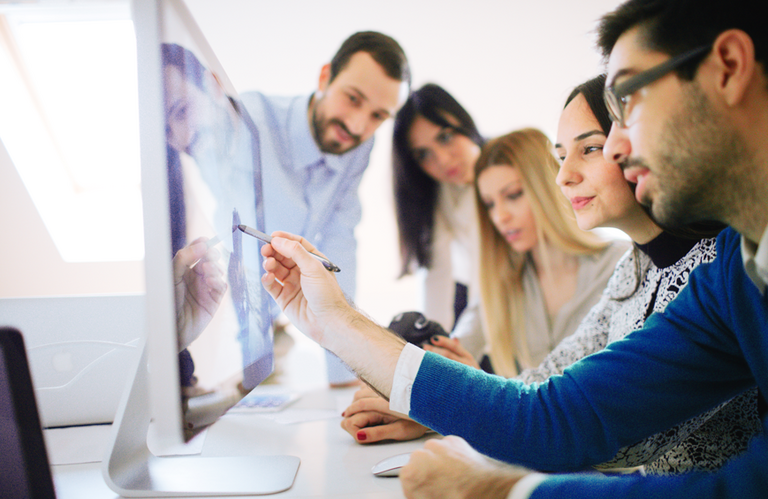 Fünf Mitarbeitende schauen sich ein Modell auf einem Monitor an