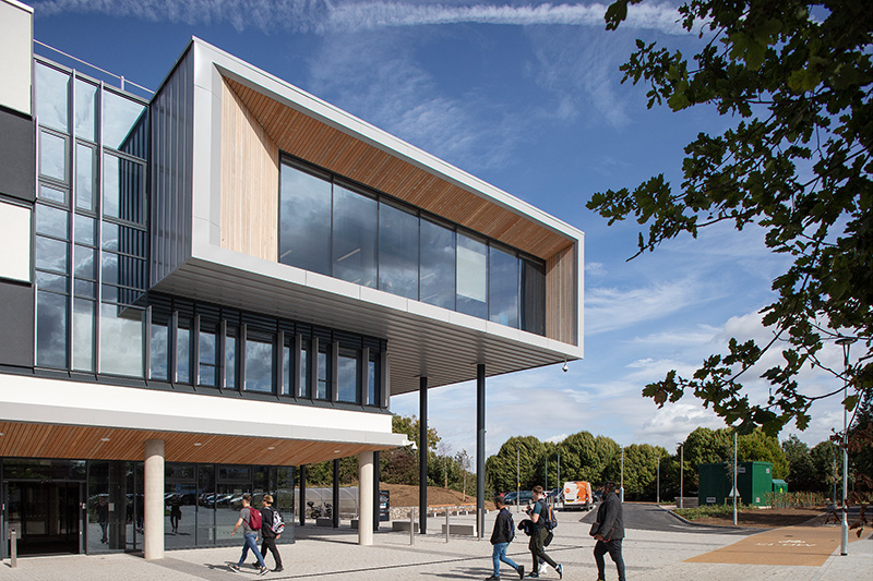 The picture shows a modern building with a facade made of aluminum, glass, and wood.